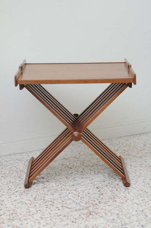 Realized in exquisite walnut, this folding Campaign tray table by Stewart MacDougall for Drexel exhibits complete versatility and mobility with high style. Wonderful tray top with carved handles and elegant touch finials at the leg axis.

Great