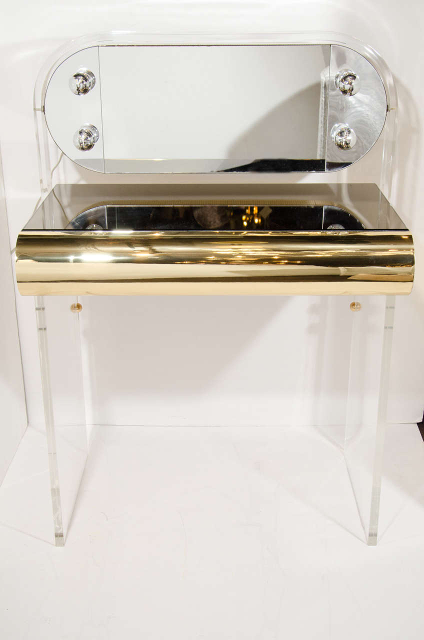 Vintage glamorous vanity table with mid century modern design in lucite. The vanity features a bronze tinted mirrored top, as well as brass banded drawer front and sides. It also features an illuminated and adjustable dressing mirror, also with
