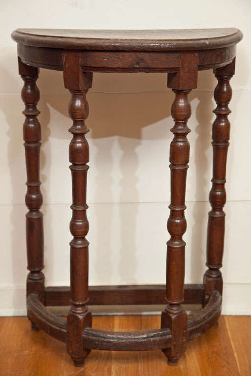 A Wonderfully pert, small but tall demi lune table of carved and turned oak.