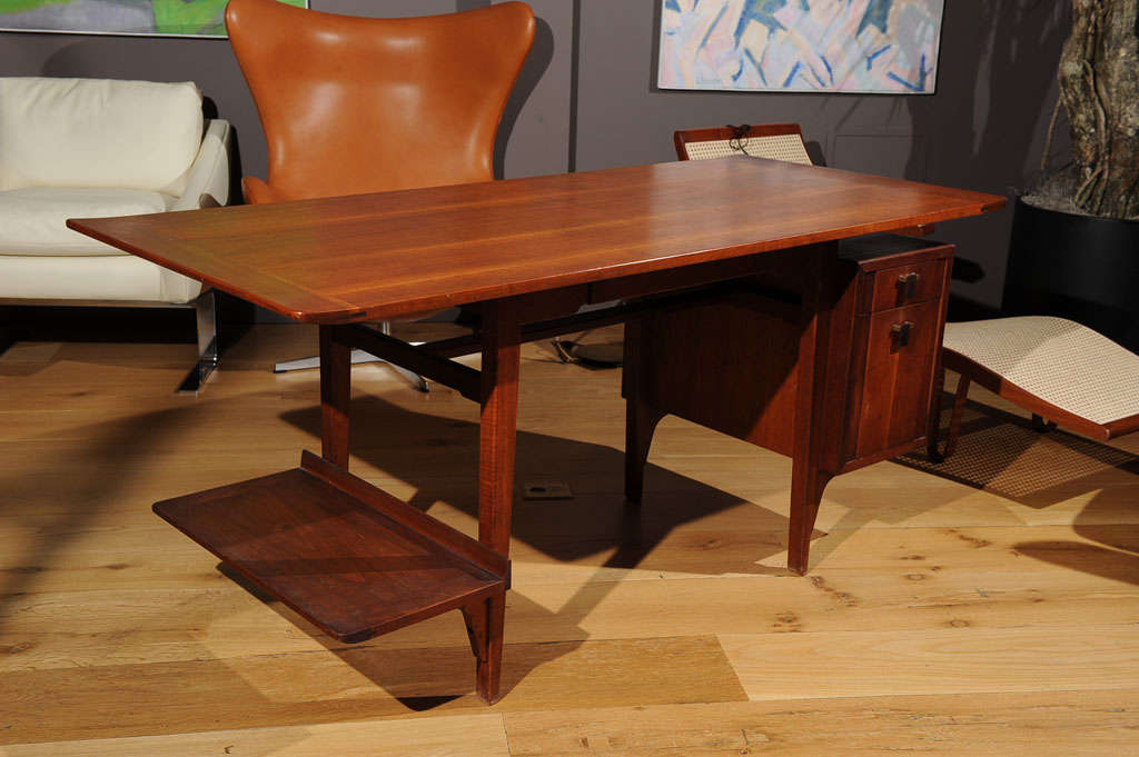 A walnut desk, model 5735, produced by Dunbar with two drawers and a low side shelf.
Signed with applied gold rectangular manufacturer's label to drawer: [Dunbar Berne, Indiana]