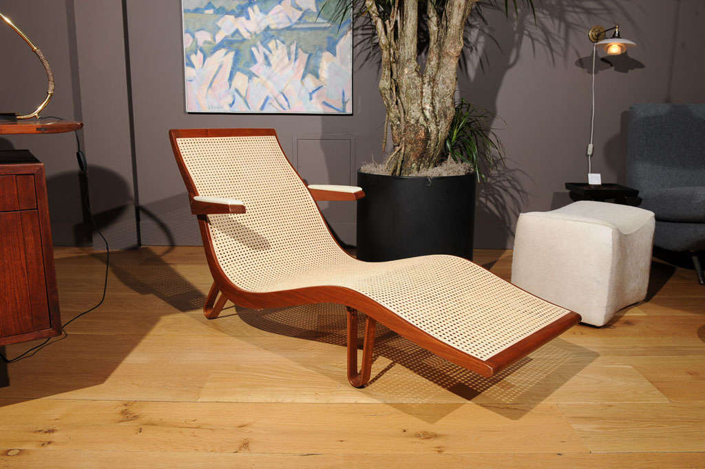 A bleached mahogany chaise lounge with white leather armrests and a newly restored cane seat and back.