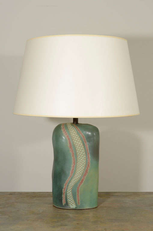 The shaped ceramic lamp base with an irregular incised band on a green glazed ground.