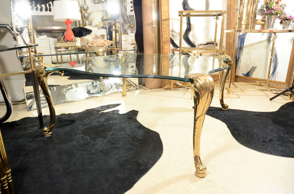 This very decorative, midcentury cocktail table is by the French decoration firm Maison Jansen and is from the mid-1950s. The finely detailed legs are made of solid brass. The glass top is new, designed in the same shape as the original. The glass