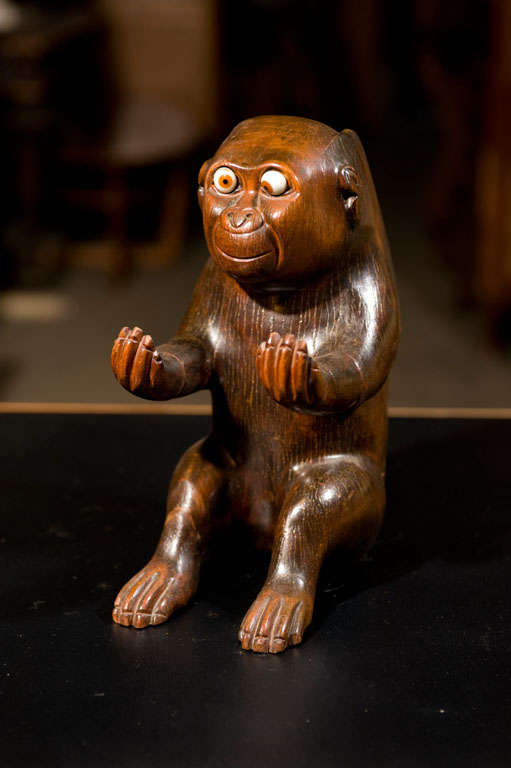 An amusing carved spill vase shaped as a monkey with porcelain eyes