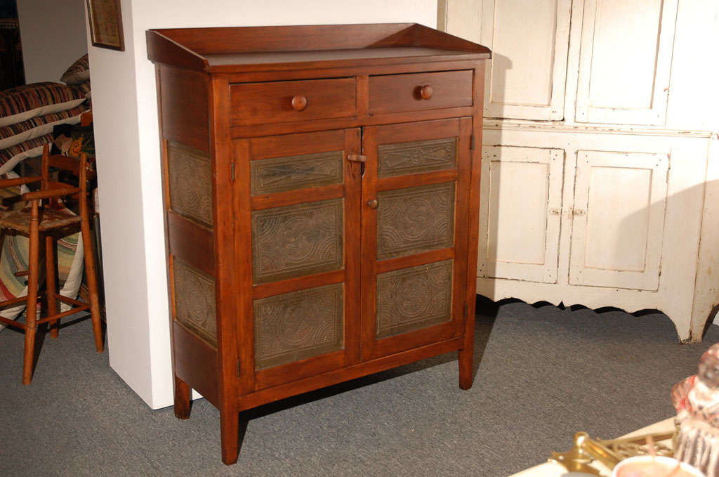 GREAT TWO DRAWER OVER TWO DOOR PIE CUPBOARD WITH FANTASTIC PENNSYLVANIA DUTCH PUNCHED TIN PANNELS.THIS WALNUT AND PINE COMBINATION PIE SAFE/CUPBOARD IS IN GREAT CONDITION WITH A OLD STAIN FINISH.THE SURFACE OF THE ORIGINAL TINS AND WOOD IS