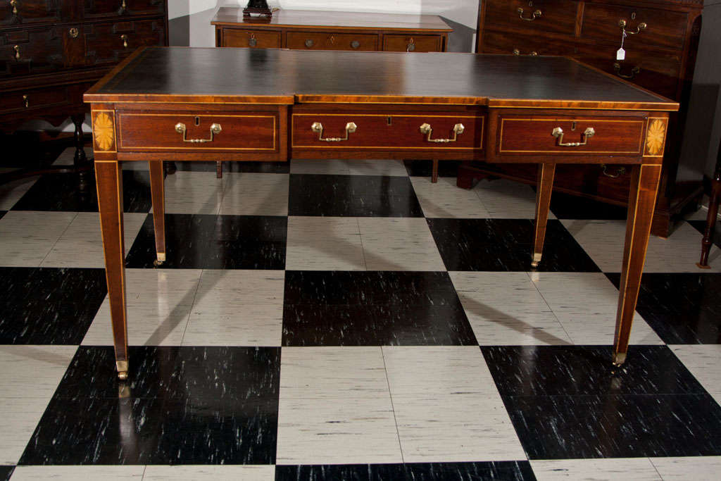 Mahogany shaped top partners writing table with satinwood stringing and inlaid fan medallions. Black/green, antiqued and gold tooled leather top. Three drawers each side with antiqued brass bail hardware; tapered legs with satinwood stringing ending