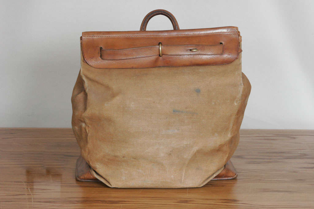 A Steamer Bag originally designed to be kept inside the trunks hence its soft canvas and folding form. <br />
Tan leather tab stamped 
