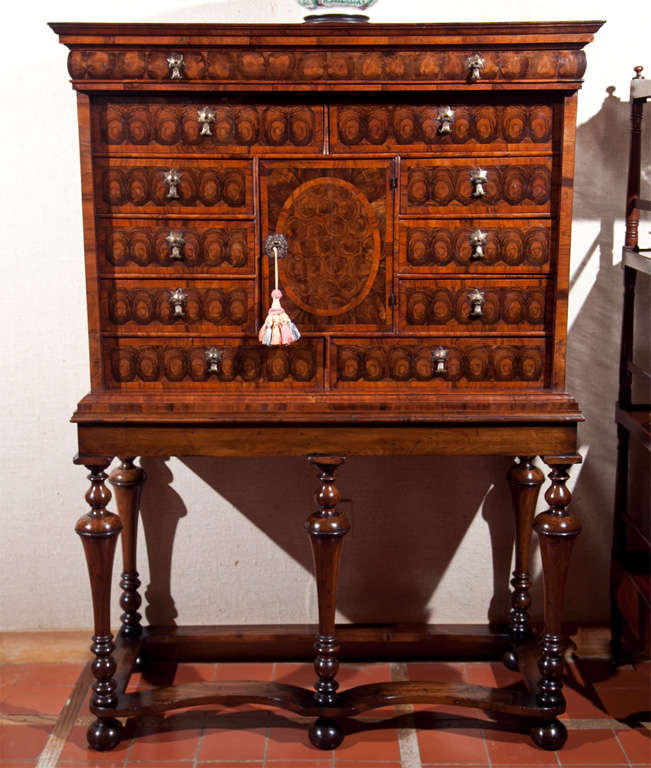This is an exquisite example of a late 17th-early 18th century cabinet in oyster cut laburnum and walnut. Containing eleven drawers of varying size with a central cupboard, itself housing a mirror that flips up to reveal a hidden compartment with