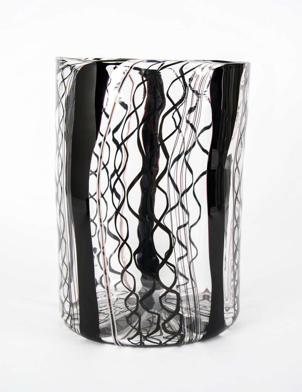 Large scale blown glass vessel. Clear crystal with black cane work.

‘In this series of objects I have used the classic techniques of canes and murrinis but worked with a more organic approach to create the loose patterns in the glass that I am