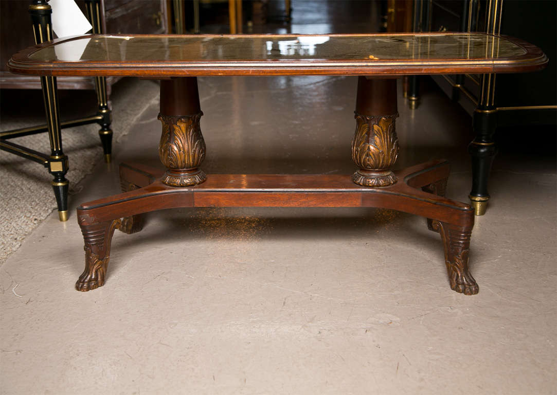 French mahogany coffee table with gilt-glass top, circa 1940s, supported by two short pedestals, raised on splayed legs ending in claw feet. Stamped Jansen.