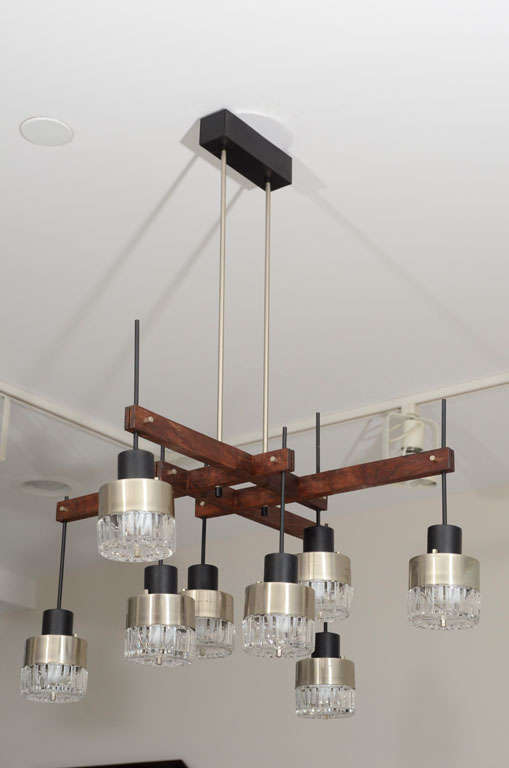 Eight-light chandelier of steel downlights with cut-crystal covers on a wood frame with two-rod canopy.