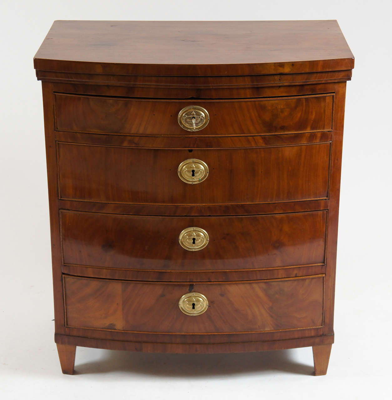 Wonderful circa 1800 Danish mahogany commode of bow-front form having four graduated drawers with exquisite original large scale gilt bronze neoclassical motif key-hole escutcheons and original working key.
