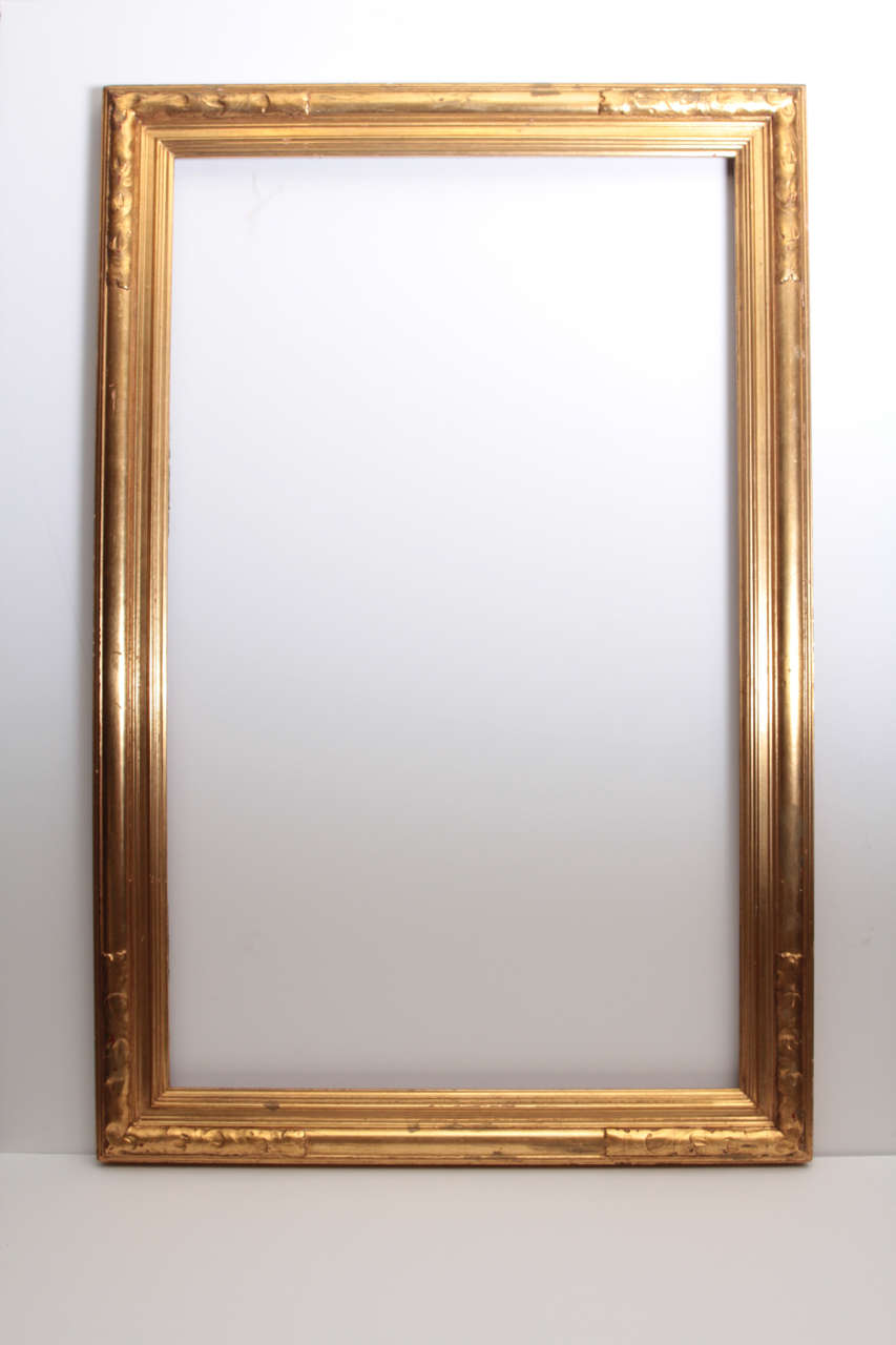 Early 20th century Arts & Crafts frame, corners decorated with undulating foliate motif, original gilt surface

Rabbet: 32 x 19 3/4 inches

Custom flat or beveled mirror can be added at an additional charge.