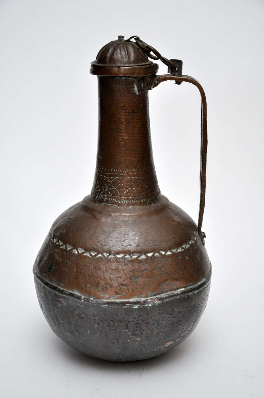 This item is a hammered copper water jug from Mali. The jug can be opened and closed at the top using a lid secured by a small chain.

Diameter at opening is 4