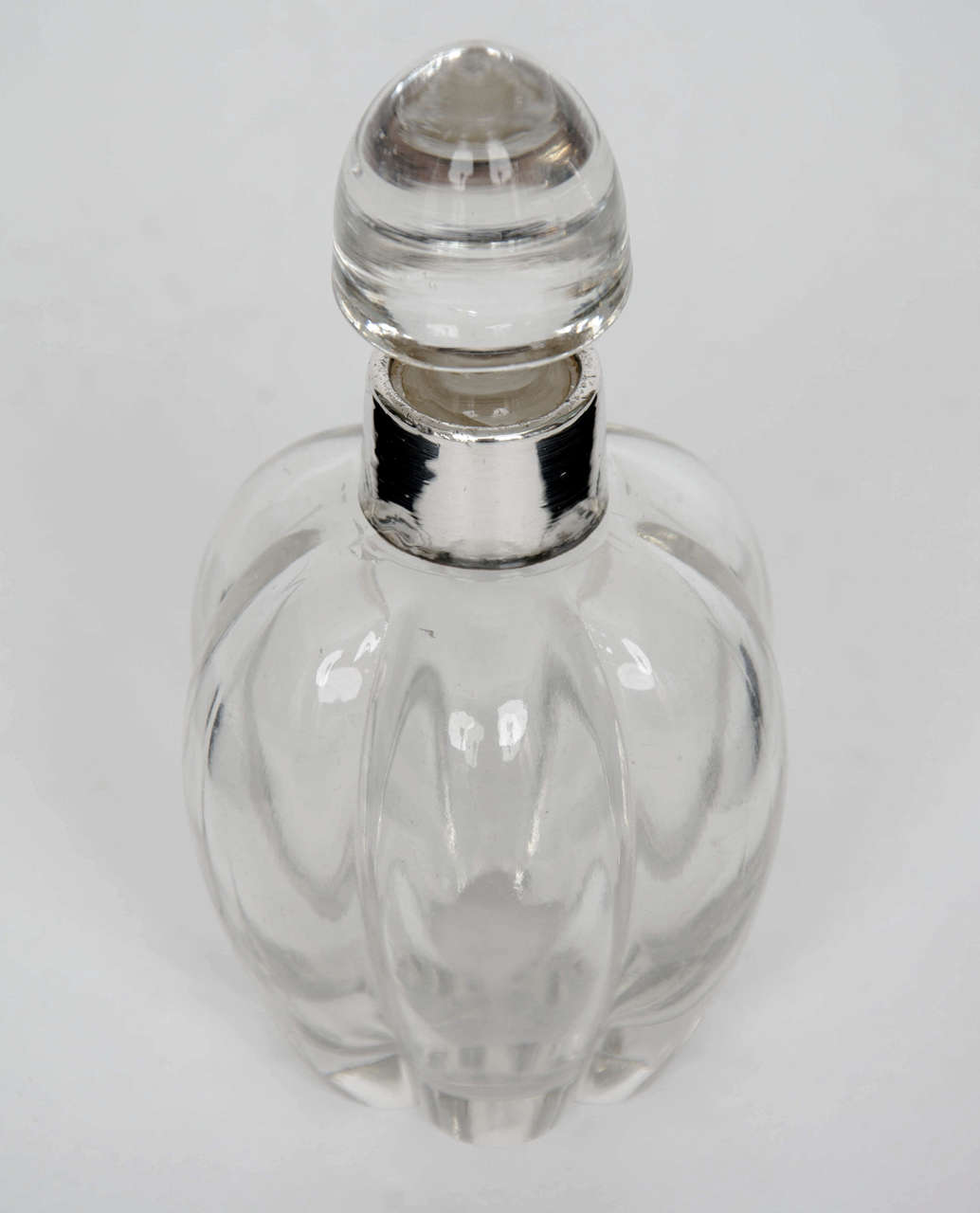 This is a beautiful perfume bottle from the Edwardian period of the early 20th century.

The bottle is made of glass, the body having six vertically fluted sections which form a baluster shape, drawing together at the neck with a solid silver neck