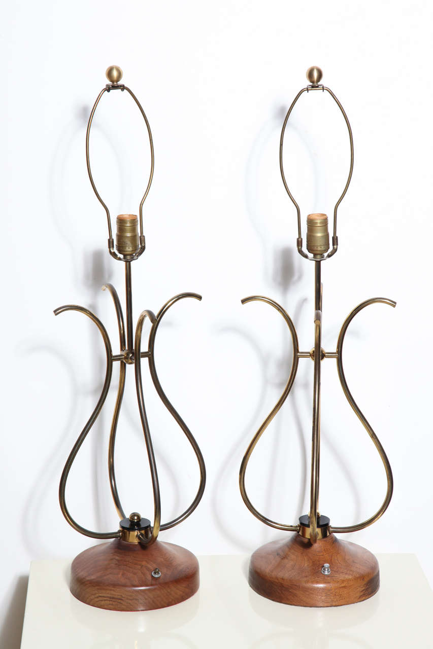 Pair of sculptural french style scrolled Brass Wire and Walnut Table Lamps.  Featuring four joined curved S shape patinated Brass wire forms, a top lightly restored solid grained Walnut 8D bases with Black Lucite disks and Brass knob detail.