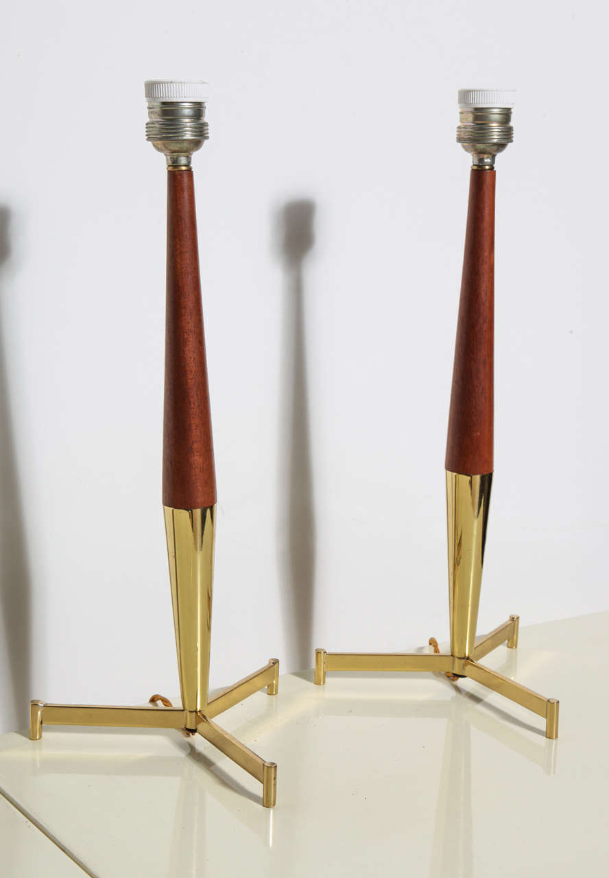 Pair of slender, elegant French Teak and Brass Candlestick Bedside Lamps from the 1960's.  Featuring a slender Teak and Brass stem with Brass tripod legs. Ceramic socket. Made in France.  Nice Boudoir Lamps, Vanity Lamps, Study Lamps, Den Lamps,