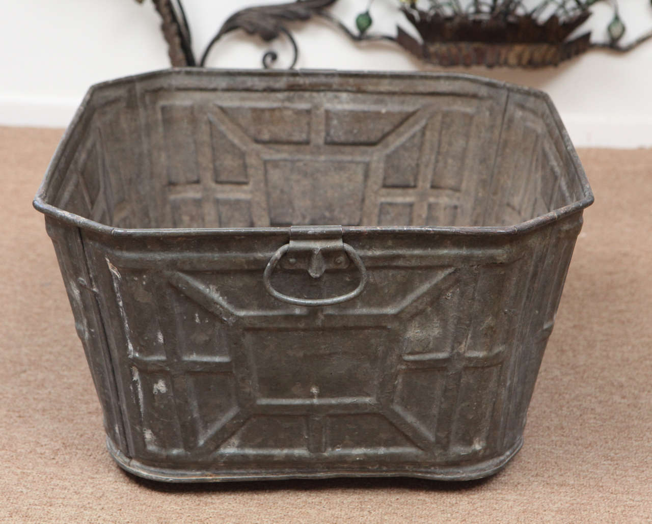 This unique item is a rare 1930's industrial piece with pressed metal art deco designs and a really nice geometric shape. The large metal tub with two handles would work well as a fireplace accessory or container for any number of items. It is
