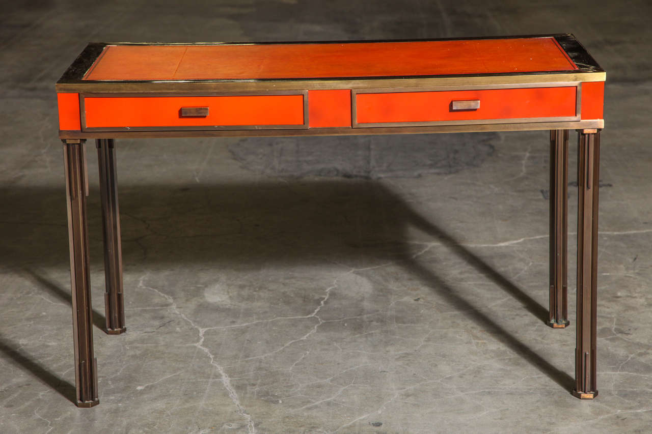 An exceptional bronze desk with orange lacquered frieze and hand-tooled leather top, circa 1960.