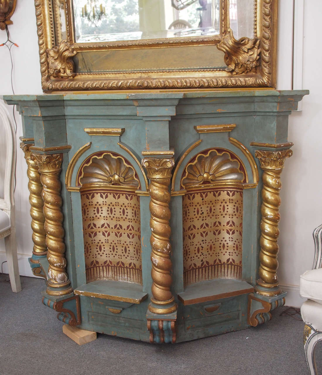 Originally part of a larger architectural structure, this carved wood piece stands beautifully on its own. It is a faded Venetian blue with gilt and gold accents; it houses three-arched intricately stenciled concave niches surmounted by a shell