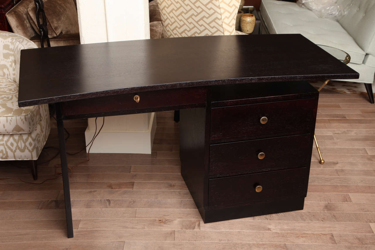 Four drawer moderne desk with cantilever top and brass hardware.