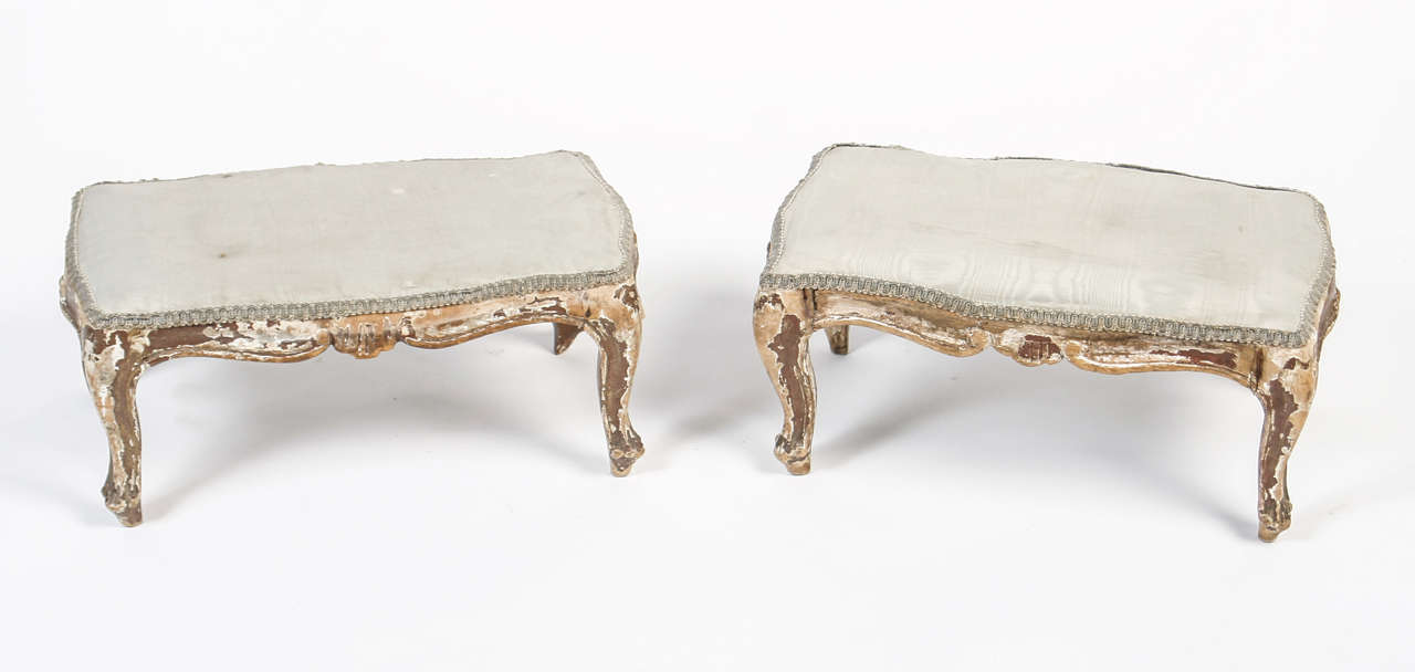 Distressed, painted, carved foot stools with later fabric tops.  Provenance Pamela Harriman, former U.S. Ambassador to France.