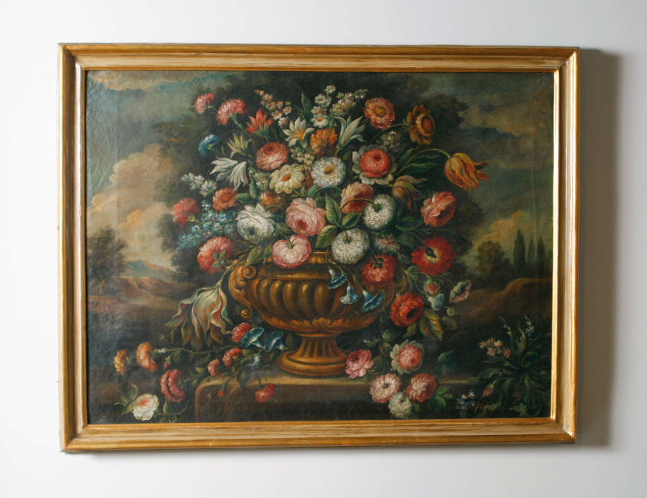 Still life depicting urn with flowers within landscape.  Oil on canvas.  Later painted frame.