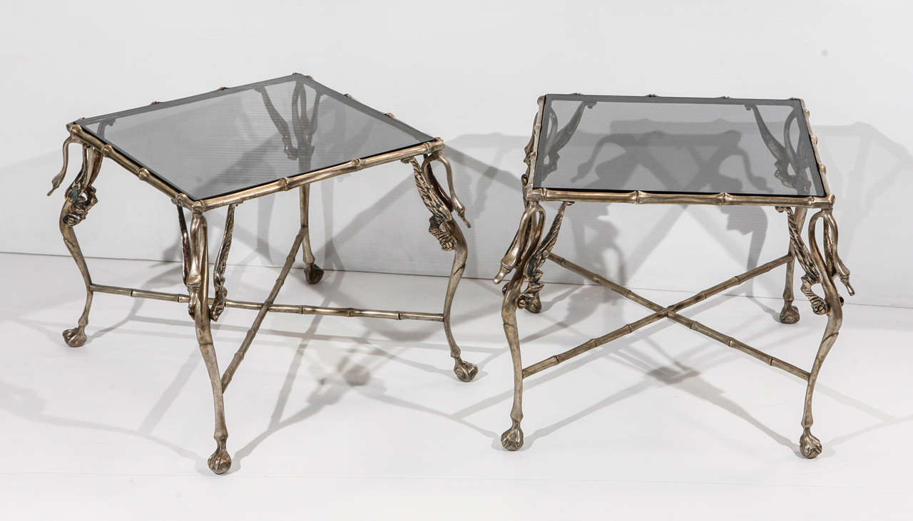 Stylized pair of nickel faux bamboo end tables having inset smoked glass supported on swan from legs with X-form stretcher