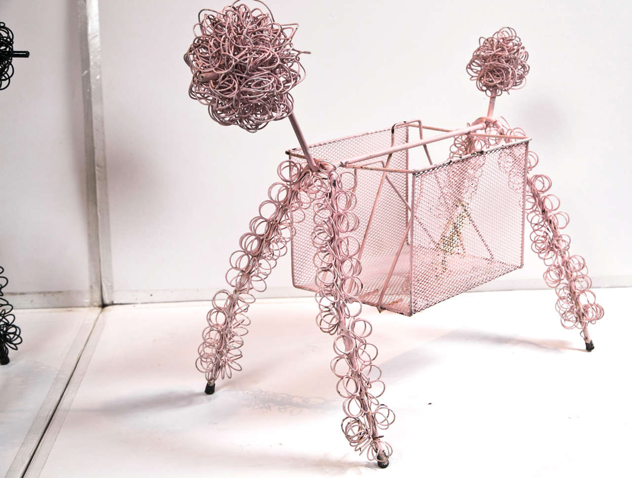 Pink painted abstract wire poodle magazine holder.