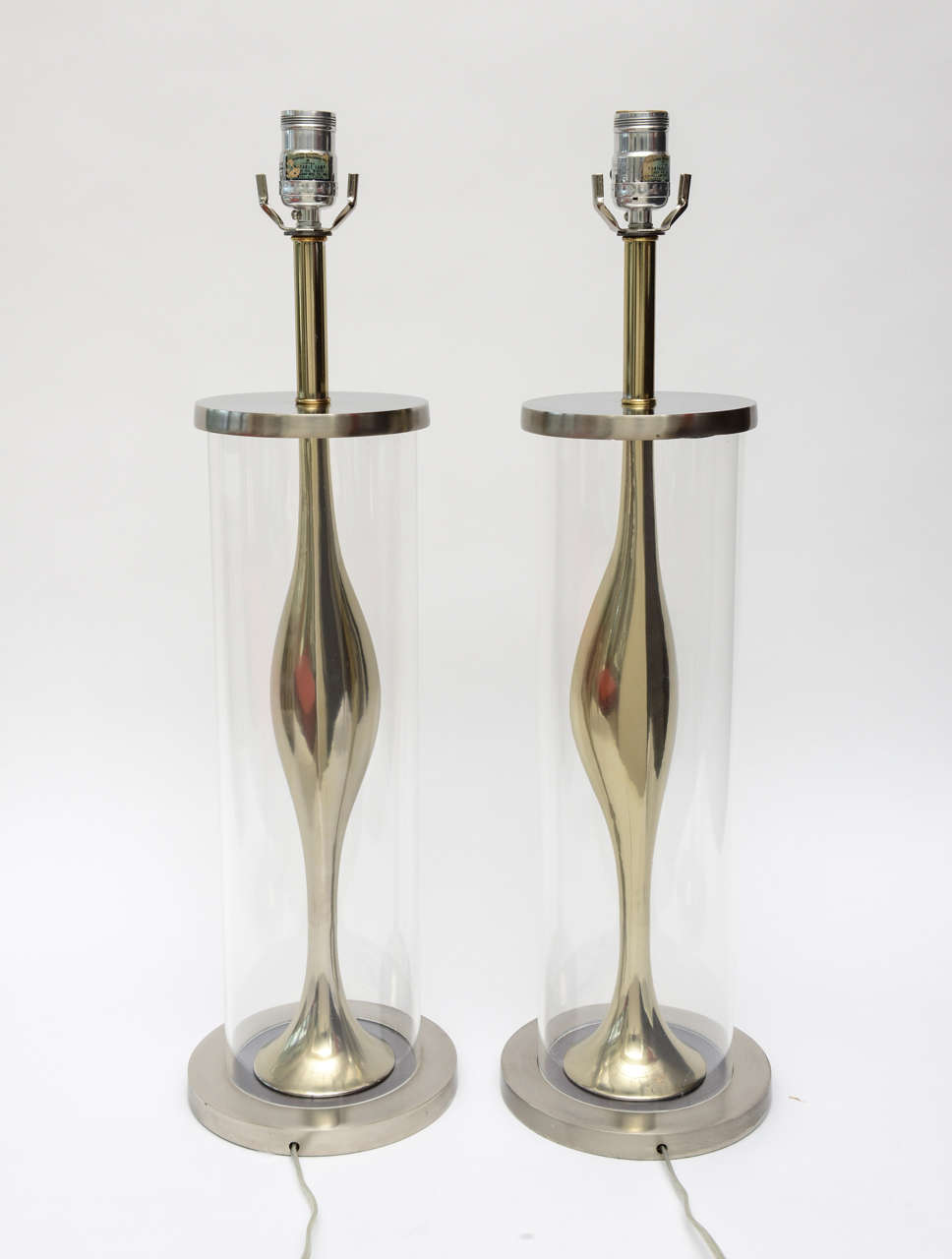 These very sculptural pair of Mid-Century Modern Laurel lamps are unusual, they have brushed stainless and polished brass with a lucite cylinder on the outside encasing the metal work. They have a sensuality to them in their form. Laurel Lamp Co.