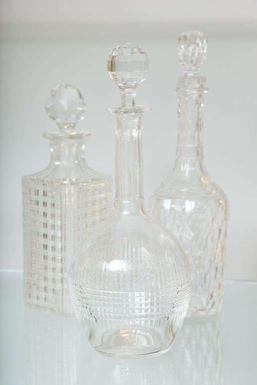 A set of three crystal decanters from three different crystal houses (Baccarat, St. Louis and American Brilliant Cut) in three different shapes that look great as a trio on a bar.