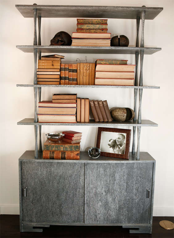 Attractive modernist bookcase from the 1950's, in a cerused grey finish.  Storage shelves underneath behind two sliding doors with polished chrome pulls.