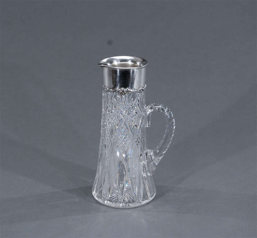 A beautiful, pristine example of a combination of America's finest craftsmen, Gorham sterling silver mount over a signed Hawkes American Brilliant period champagne pitcher. The handblown crystal is finely cut with an applied handle and embellished