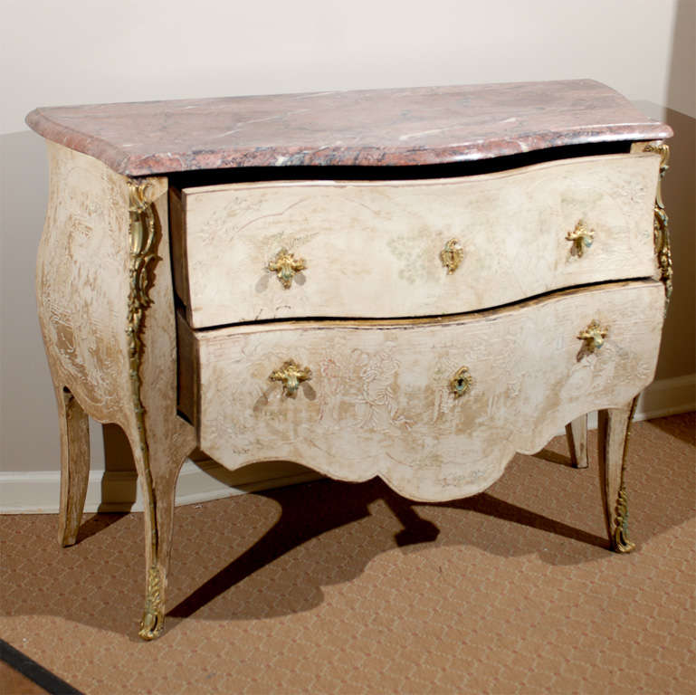 This is a beautiful, Louis XV style commode. The marble top is dominantly rosy with veined black and white running through it. The marble top is serpentine in shape, following the shape of the commode with an OG edge.
It has shallow carvings of