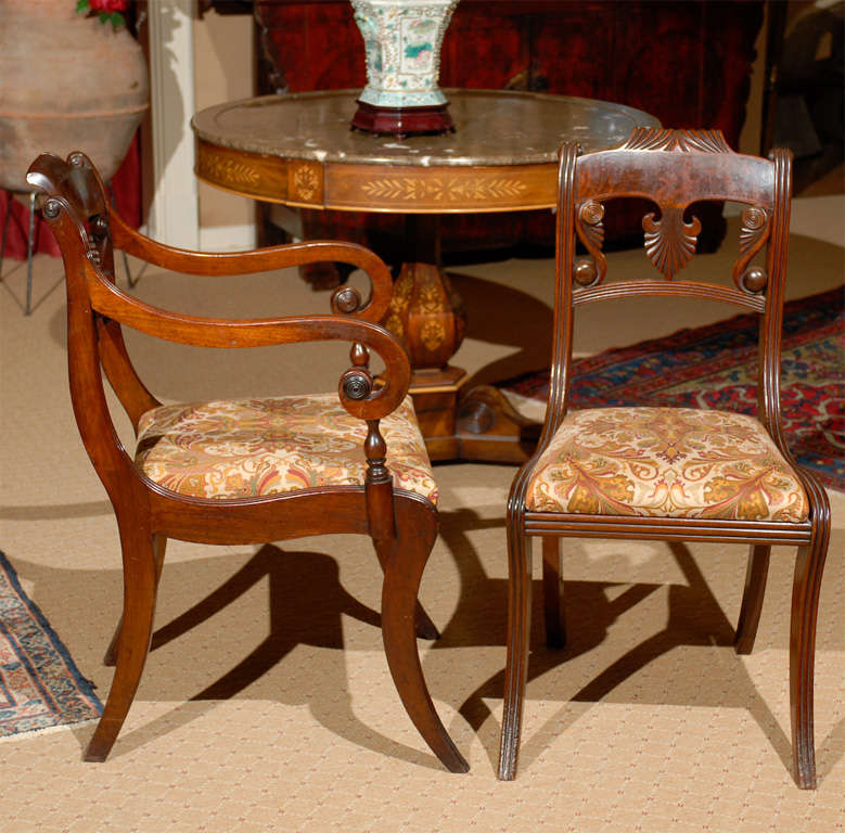 A beautiful set of two dining armchairs and four side chairs, crafted in mahogany, carved scrolled arms and Klismos style legs. Each with a scroll carved crest-rail over a carved palmette splat and backrest.