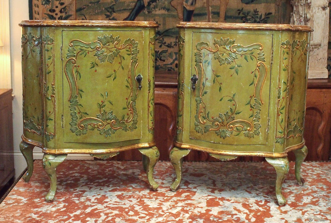 Pair of rococo style cabinets, with shaped sides and fronts, on cabriole legs.  Painted in grass green in the chinoiserie taste, with a faux marble top.  Single doors open to reveal a drawer.  Cabinet doors open in mirror image for ease of use as