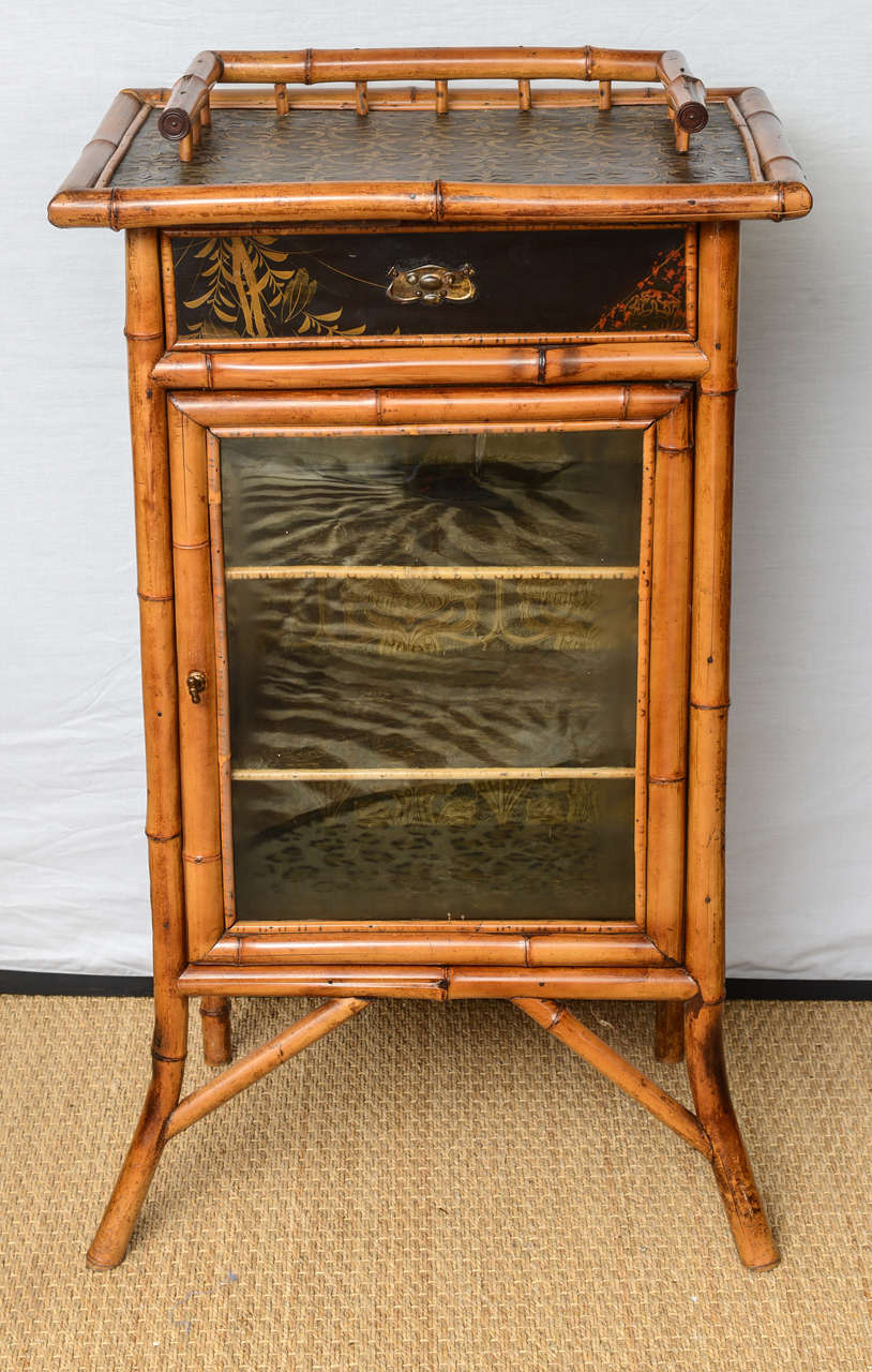 A Victorian English bamboo cabinet with lacquer and leather paper.