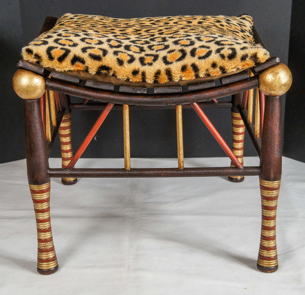 This stool made by Liberty of London is rarely seen in paint and gilded  details. Crafted in the late 19th century this stools looks back to ancient Egyptian models and is crafted by hand. In this version the legs turnings are gilded and painted in