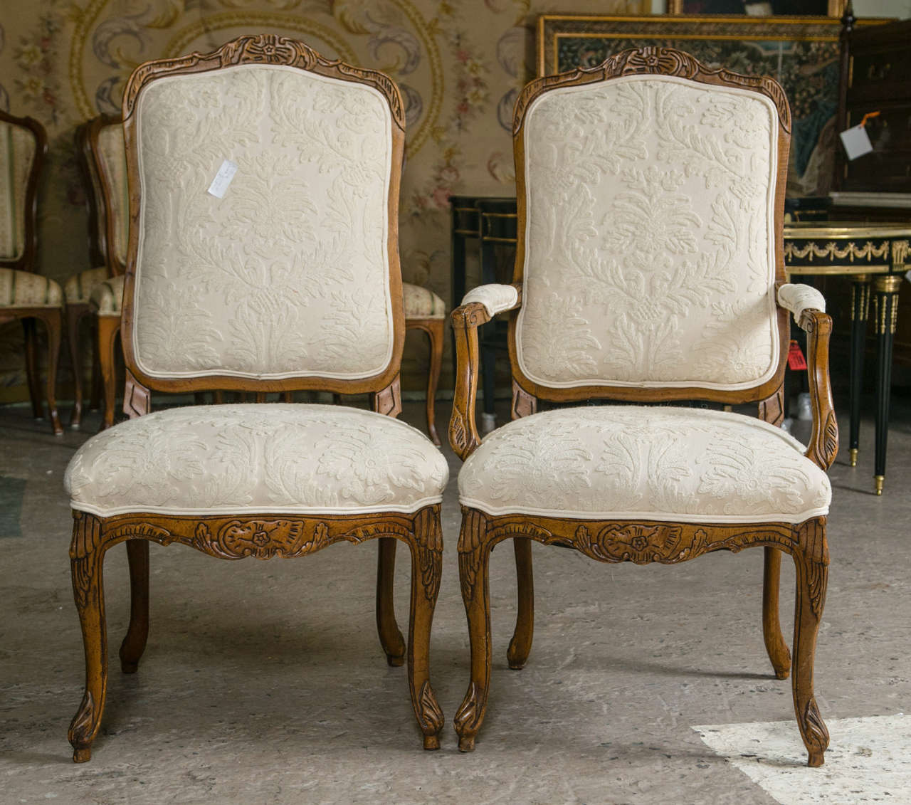 Set of 12 Louis XV style high back dining chairs. Each carved cabriole leg having a carved apron undercarriage. The wide comfortable seat each with a padded back rest with framed walnut case terminating in a carved leaf design. Can buy as many as