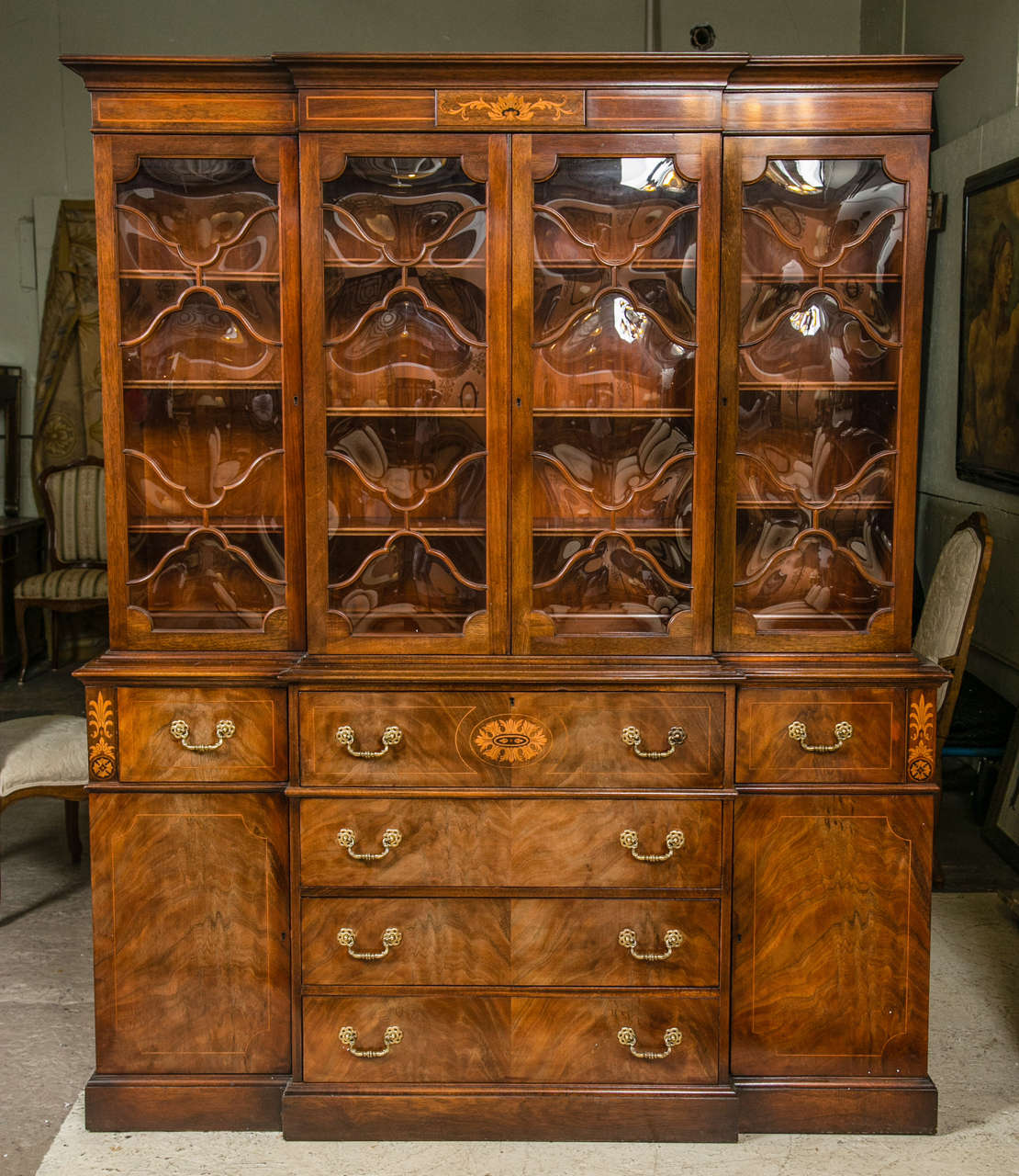 A stunning crotch mahogany breakfront bookcase. The block front case having four center drawers, the top converting to a pull down writing area with desk compartment, flanked by two large doors. The top corners and center drawer with a fine