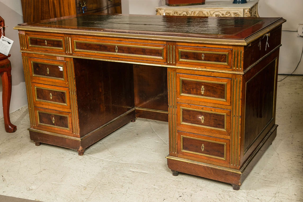 An antique Russian neoclassical knee hole desk. This finely crafted four-piece desk has a fine green tooled three-drawer leather top with pull-out sides which is framed in a mahogany bronze framed border. The base consisting of a pair of