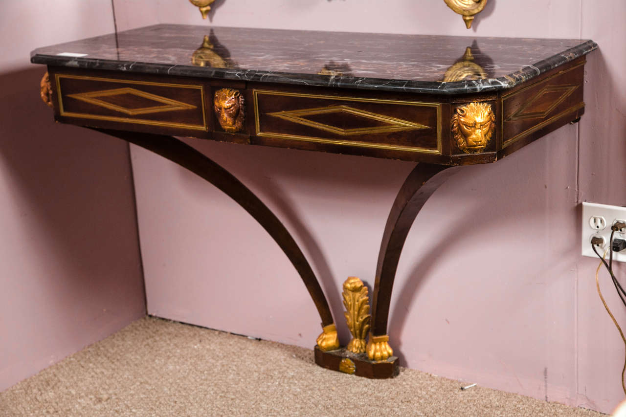 A Russian neoclassical style console table. The gilt gold decorated claw feet separated by a feather design leading to a pair of swayed open legs supporting an inlaid gilt gold lion head apron under a veined marble top.