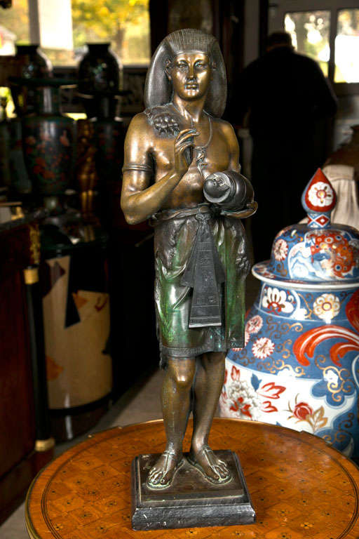 A STANDING FIGURE OF AN EGYPTIAN SCRIBE, SIGNED ON THE BASE PICAULT (EMILE LOUIS PICAULT,1833-1915) COLD PAINTED AND  RICHLY PATINATED. HE WEARS A HEADDRESS, A LION SKIN OVER HIS SHOULDER, AN AMULET  AROUND HIS NECK, HOLDING A COPTIC JAR WITH THE