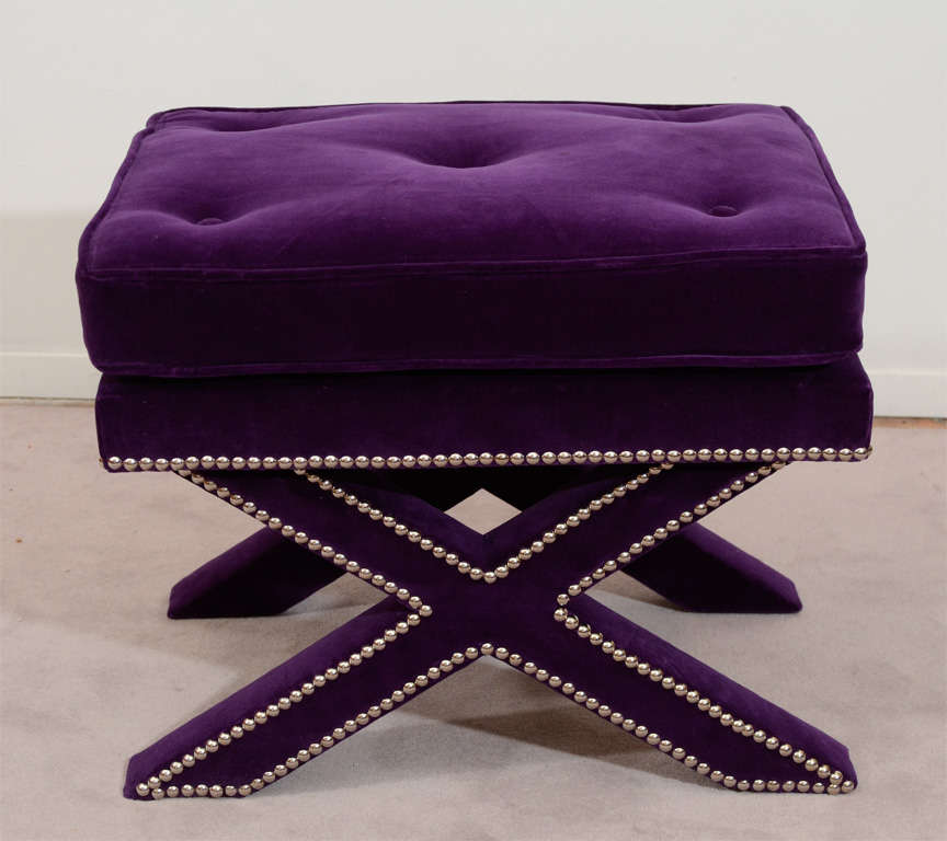 A pair of vintage stools with x-form bases and silver nail-head detailing. They have been newly reupholstered in tufted purple velvet.