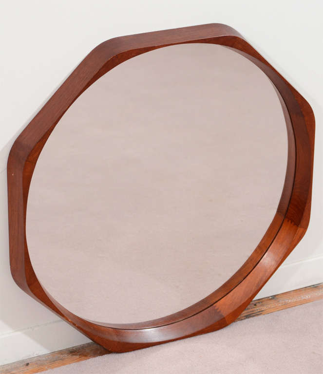 A vintage wall mounted round mirror set in a wooden octagonal frame.