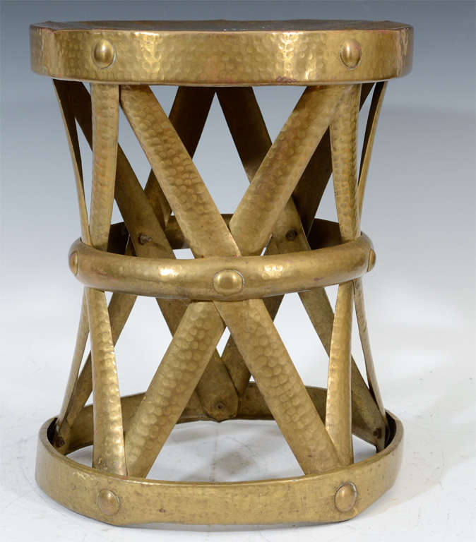 A vintage drum-form stool or table in hammered brass with an aged patina. The piece is by Sarreid.