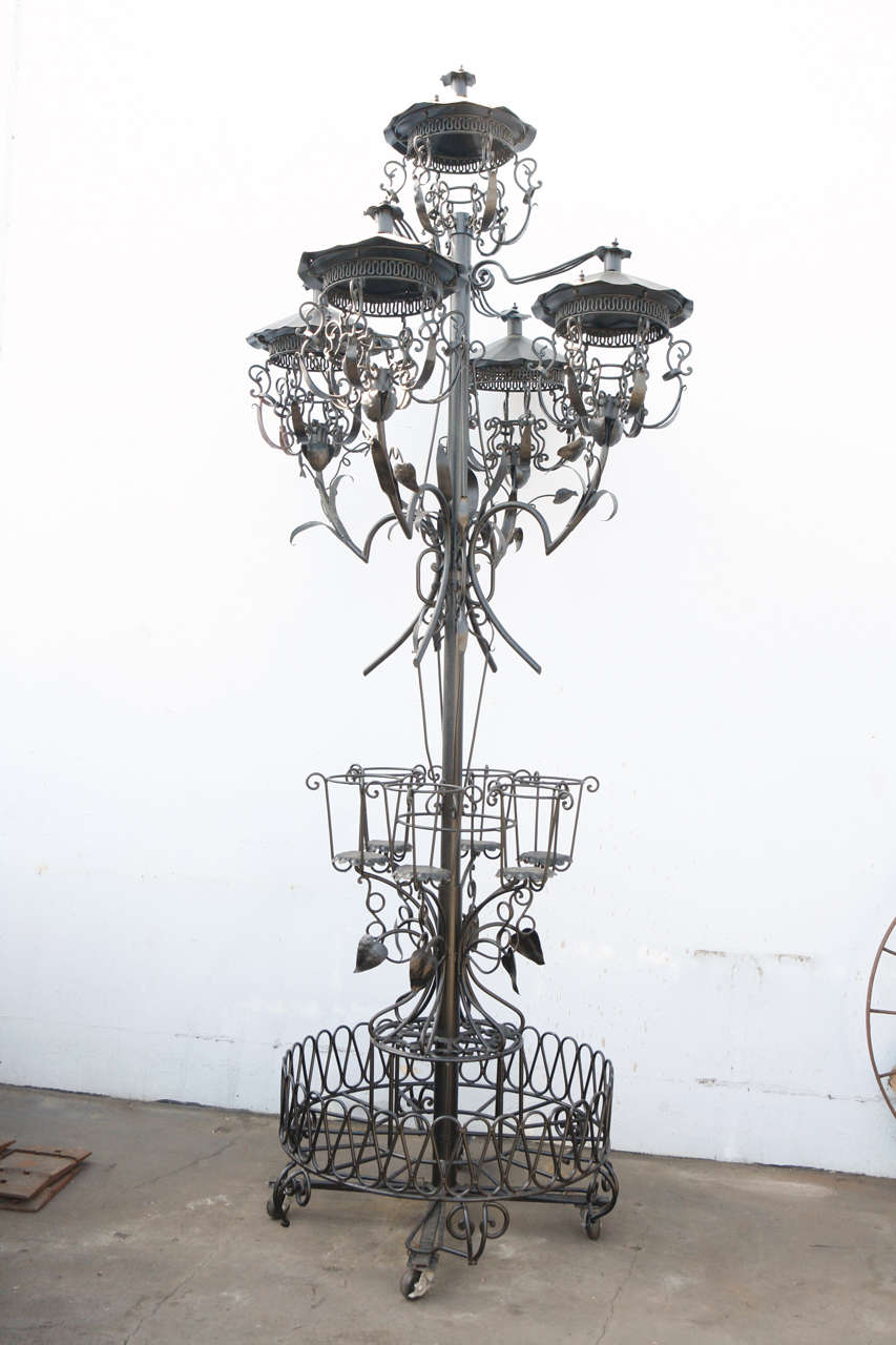 Hand wrought in iron this larger garden centerpiece will standout and add interest to any garden or patio or other location. The centerpiece is adjustable from nine to thirteen feet in height. The five, light holding, elements are detachable along