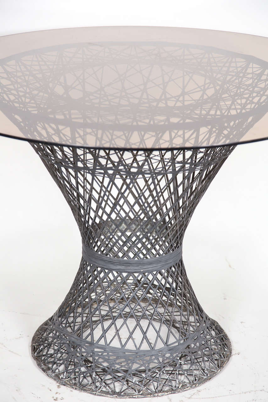 Set consists of four chairs with cushions and one table with round glass top. Table and chairs are made out of a metal mesh that closely resembles wicker.