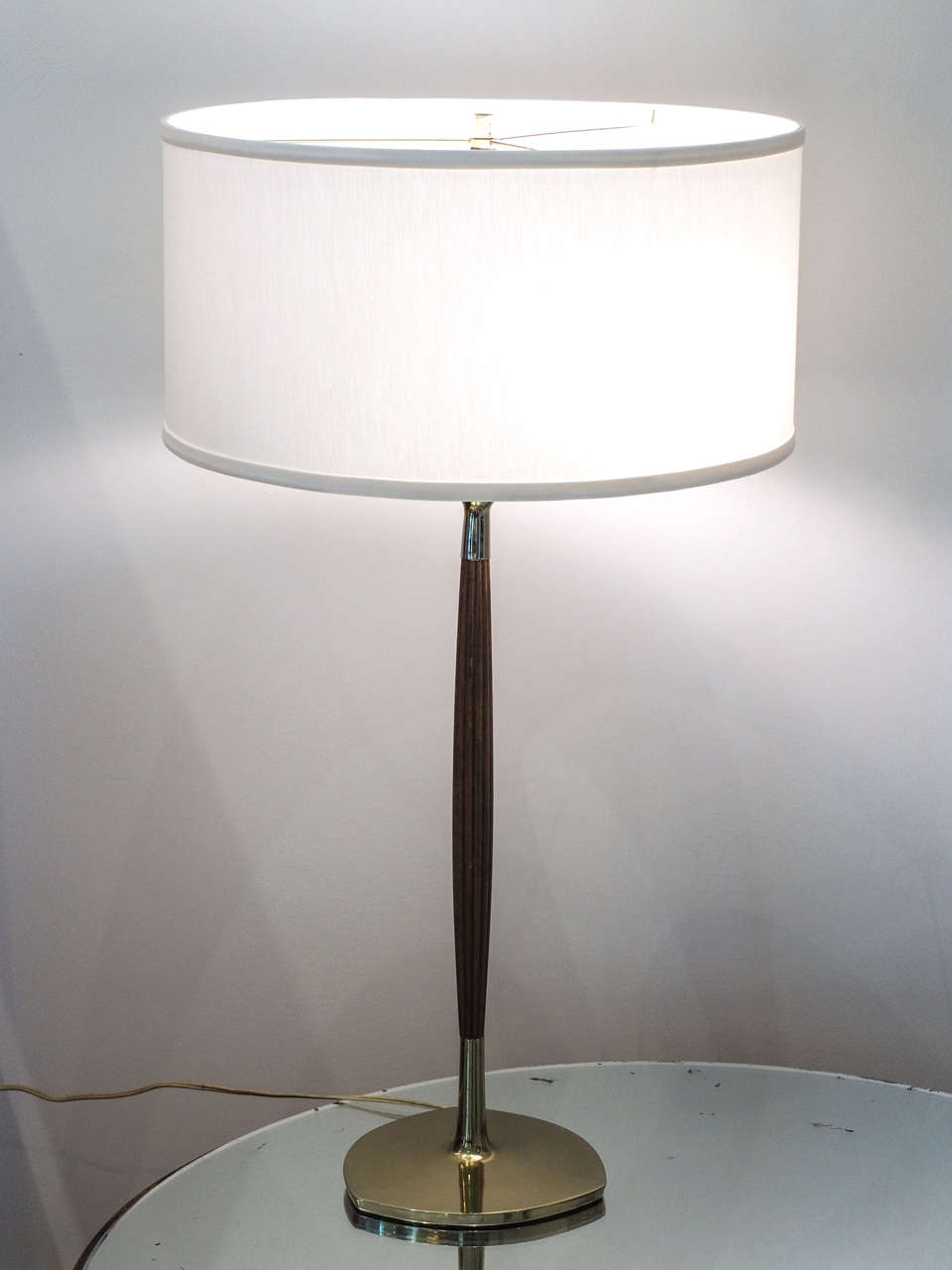 Attractive attenuated three-light table lamp in walnut and brass with ivory silk shade; paper Laurel label on one socket; white painted metal diffusor below the light sources; triangular brass base with rounded sides
