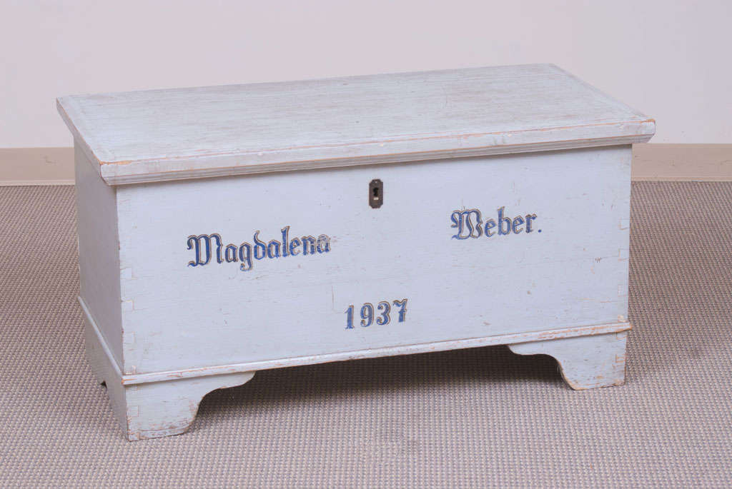 A pine blanket chest on bracket feet and in original powder blue paint with deep blue inscription on the front. The lid lifts on iron strap hinges to reveal an exceptionally clean interior and complete candle box.